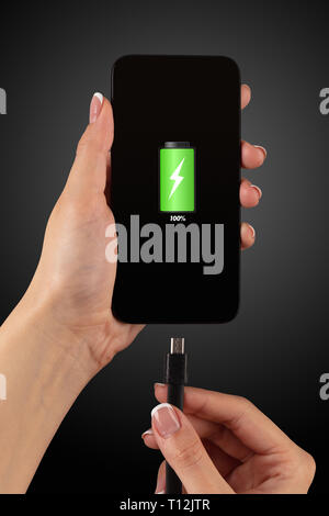 Elegant hand charging cellphone with low battery  Stock Photo