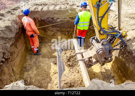 Workers are using metal measure tape, meter to check measurement in square trench. Stock Photo
