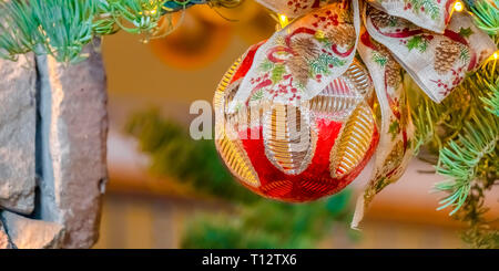 Illuminated Christmas Tree with bauble and ribbon. Close up of an illuminated Christmas Tree with embellished bauble and ribbon. The tree is set again Stock Photo
