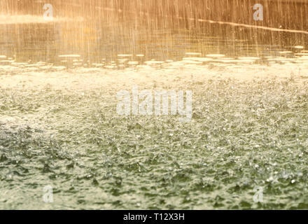 Droplets hitting water surface. Raindrops falling on the green surface of the water. Vintage stylized. Motion blur. Stock Photo