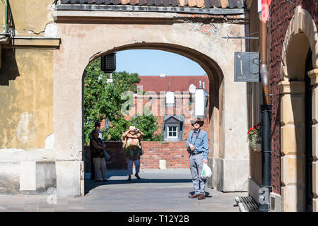 Warsaw, Poland - August 22, 2018: Old town cobblestone street during summer day and arch archway with tourists Stock Photo