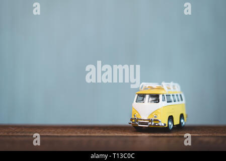 Yellow vintage miniature van on a wooden table. Concept of travel and transportation. Shallow Depth of field with selective focus Stock Photo