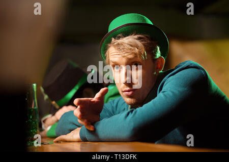 Fair-haired young handsome man in a green looking surprised Stock Photo
