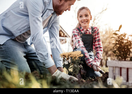 Smiling long-haired daughter helping his stunning father Stock Photo