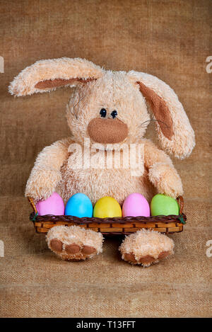 Stuffed soft rabbit with colorful bright painted eggs. Stock Photo
