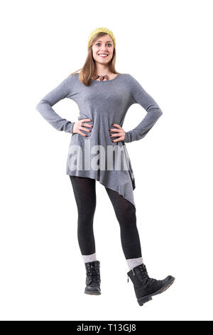 Young stylish woman wearing tights, boots, gray tunic and yellow beanie cap smiling. Full body isolated on white background. Stock Photo