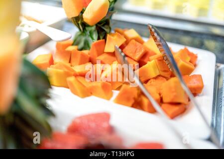 Close up of fresh and delicious diced organic mango fruit cubes on a buffet bar with serving tongs. Stock Photo