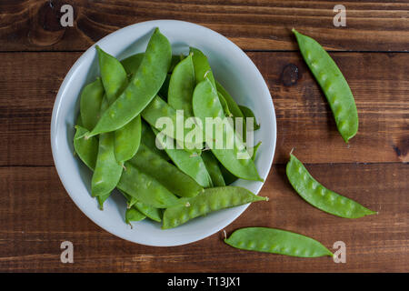 Snow peas inside bowl on wooden table background Stock Photo