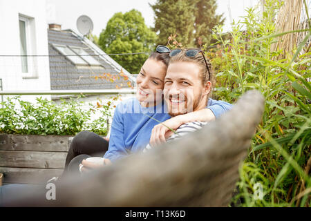 Young couple relaxing on their balcony, sitting on couch Stock Photo