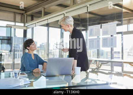 Two smiling businesswomen discussing at desk in office Stock Photo