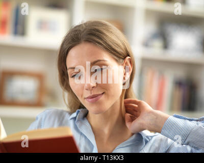 Young woman relaxing at home reading a book Stock Photo
