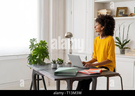 Woman sitting at desk, working, using laptop Stock Photo
