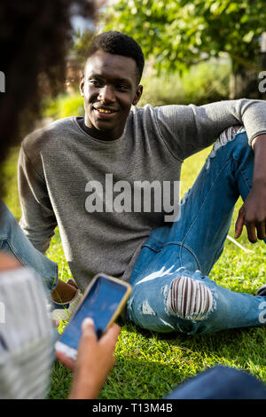 Friends with smartphones spending time in a park Stock Photo