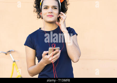 Smiling young woman with smartphone listening to music Stock Photo