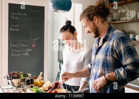 Young couple preparing food together, tasting spaghetti Stock Photo