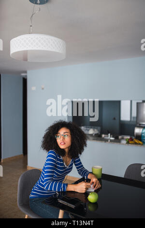 Portrait of young woman sitting at table at home taking notes Stock Photo