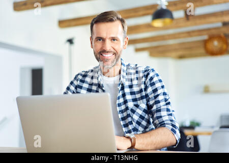 Portrait of man working remotely on laptop and looking at camera Stock Photo