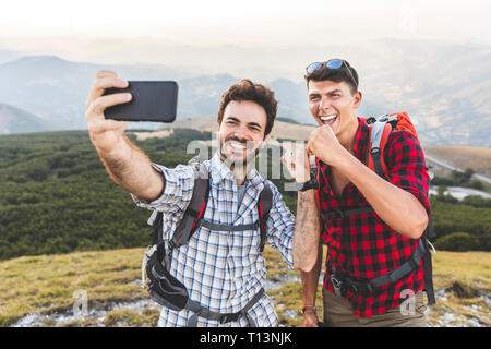 Italy, Monte Nerone, two happy hikers on top of a mountain taking a selfie Stock Photo