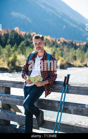 Austria, Alps, man on a hiking trip with map on a bridge Stock Photo