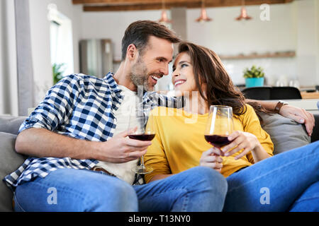 Happy couple sitting in living room, drinking red wine Stock Photo