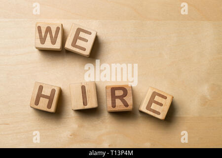 We Hire written on wooden cube blocks on wooden office table - human resources or job vacancy concept Stock Photo