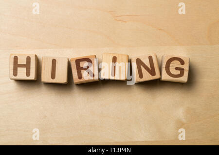 Hiring written on wooden cube blocks on wooden office table - human resources or job vacancy concept Stock Photo