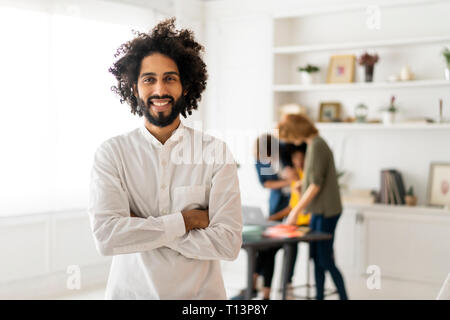Portrait of a young man with colleagues, working in  a coworking space Stock Photo