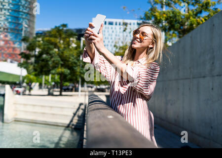 Spain, Barcelona, smiling young woman taking selfie with cell phone Stock Photo