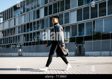 Spain, Barcelona, smiling young man walking down the street Stock Photo