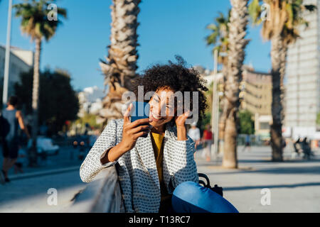 Beautiful woman sitting on a bench in the city, using smartphone Stock Photo