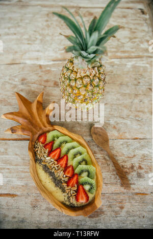 Smoothie Bowl with mango and pineapple garnished with kiwi, strawberries, chia and sunflower seed Stock Photo