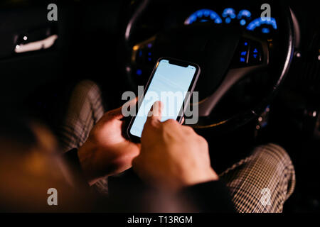 Man using cell phone in the car at night Stock Photo