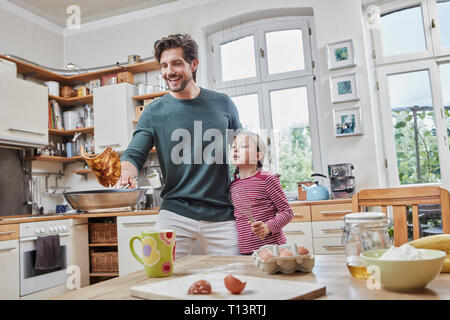 Happy father and daughter baking pancakes in kitchen at home together Stock Photo