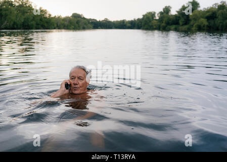 Senior man talking on cell phone in a lake Stock Photo
