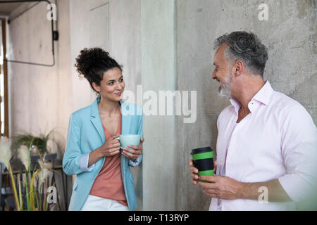Smiling businessman and businesswoman having a coffee break in a loft Stock Photo