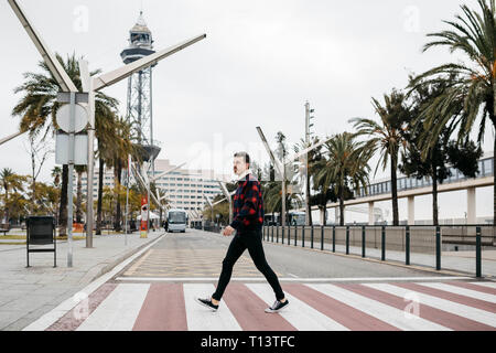 Young man with casual clothes walking on pedestrian crossing in Barcelona Stock Photo