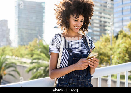 Young woman standing on a bridge, using smartphone Stock Photo