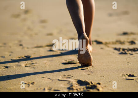 Close-up of woman's feet walking in sand on the beach Stock Photo