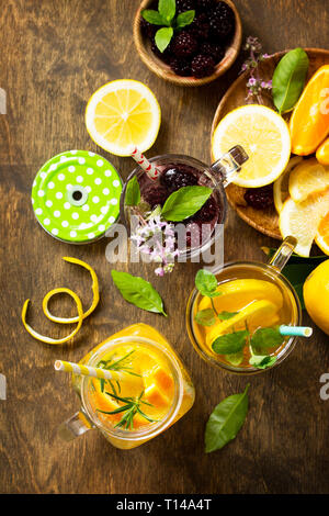 Summer drink set. Refreshing summer berry Lemonade, lemon mint Tea and orange Lemonade with rosemary. Top view flat lay background. Stock Photo