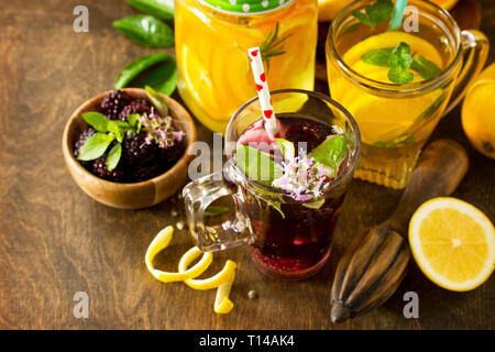 Refreshing summer berry Lemonade, lemon mint Tea and orange Lemonade with rosemary on wooden table in rustic style. Stock Photo