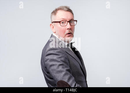 Smart senior man in suit and glasses turning back Stock Photo