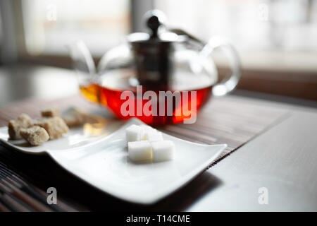 Glass transparent teapot of invigorating fresh aromatic tea on a wooden table Stock Photo