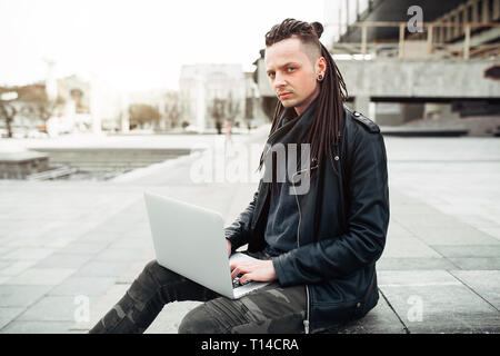 Young man sitting on the stairs using laptop Stock Photo