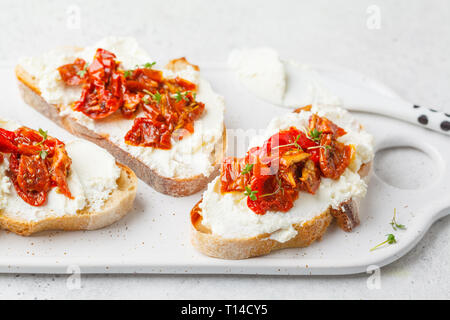 Ricotta and sun dried tomatoes sandwiches on a white board. Stock Photo