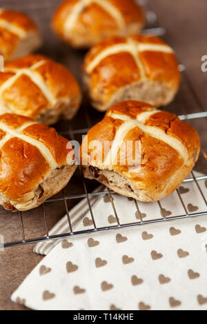Fresh hot cross buns on a cooling rack with a napkin on a stone worktop Stock Photo