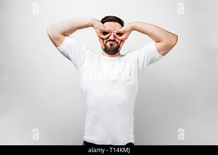 Funny and spectacular guy is and putting his arms over his eyes making some round circles. Despite he is an adult in his heart he is still a small boy Stock Photo