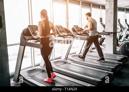 A small view of big sport room where two people are having workout. They are running on elliptical machines. The exercise is intensive and hard. Stock Photo