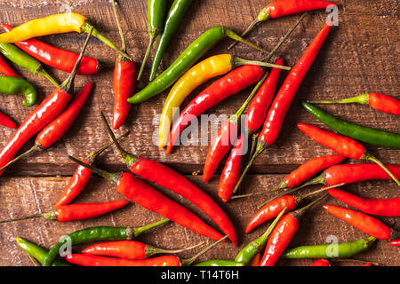 Top view the red , green and yellow chili peppers pattern over wooden background, flat lay. Stock Photo