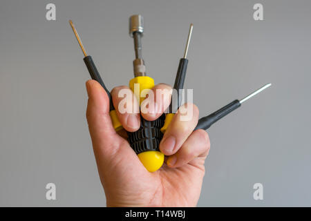 Hands raised holding different tools. Male hands with different repair tools on gray background. copy space. Stock Photo