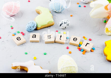 Easter colorful gingerbread cookies,  small decorative eggs in the nest and tulips on light grey concrete background, top view,  copy space, Easter gr Stock Photo